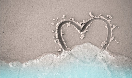 fading hand written heart shape on sand beach 