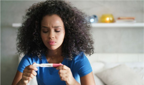Disappointed woman looking at a pregnancy test