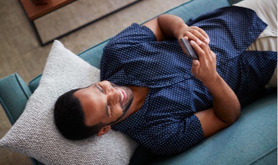 A man lying on a couch texting