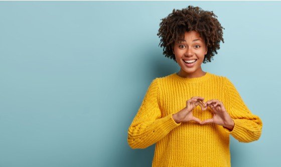 Young smiling black girl with afro making a heart sign with her fingers
