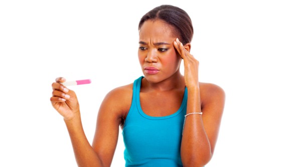 Woman looking at a pregnancy test, unhappy and confused 