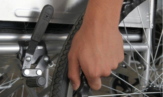 A hand holding the tyre for a wheelchair