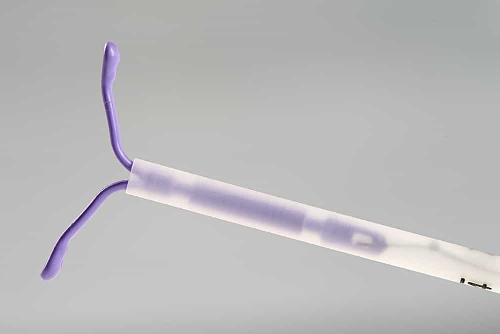 a purple IUD fitted in a clear tube