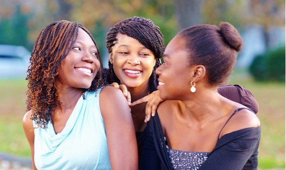 Three African girls speaking to each other and smiling