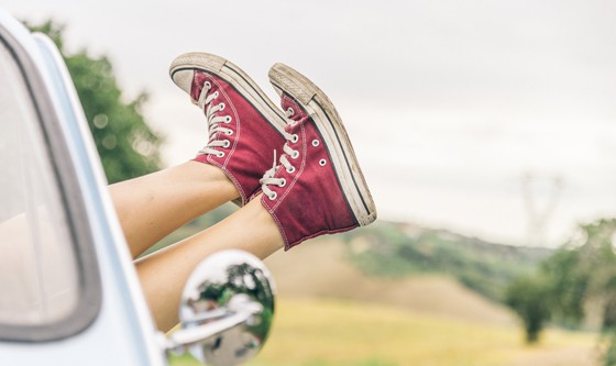 Woman's legs hanging out of a vintage car's passenger window