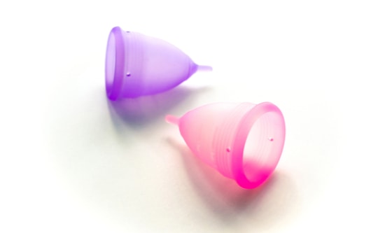 Two menstrual cups, one purple, one pink