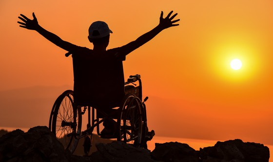Happy man in a wheelchair at sunset