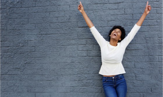 portrait of a cheerful african woman with hands raised pointing up