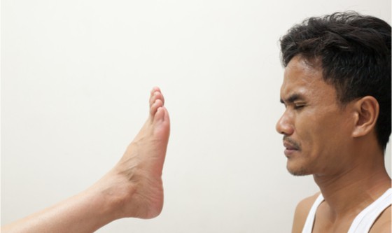 Woman's foot smelly and an unhappy man on the white wall for background.