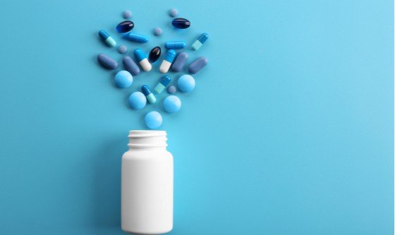 pills spilling out of a bottle on a blue background