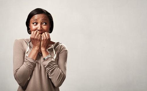 a worried woman covering her mouth with folded palms