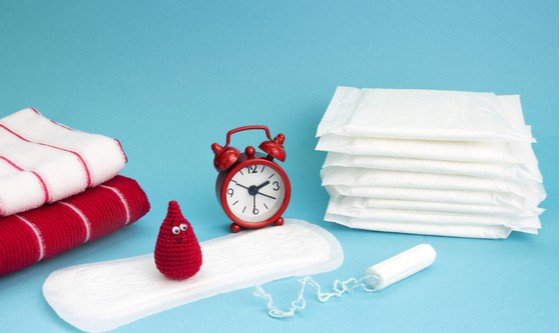 A number of pads and towels, a tampon, a red anthropomorphized period drop and a red clock