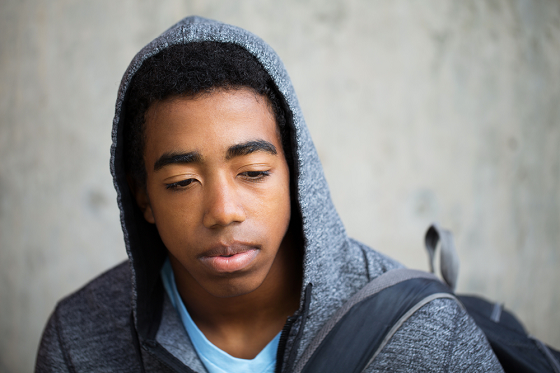 Sad young man wearing a grey hooded sweater
