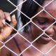 sad black woman behind mesh wire