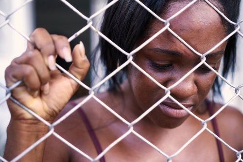 sad black woman behind mesh wire