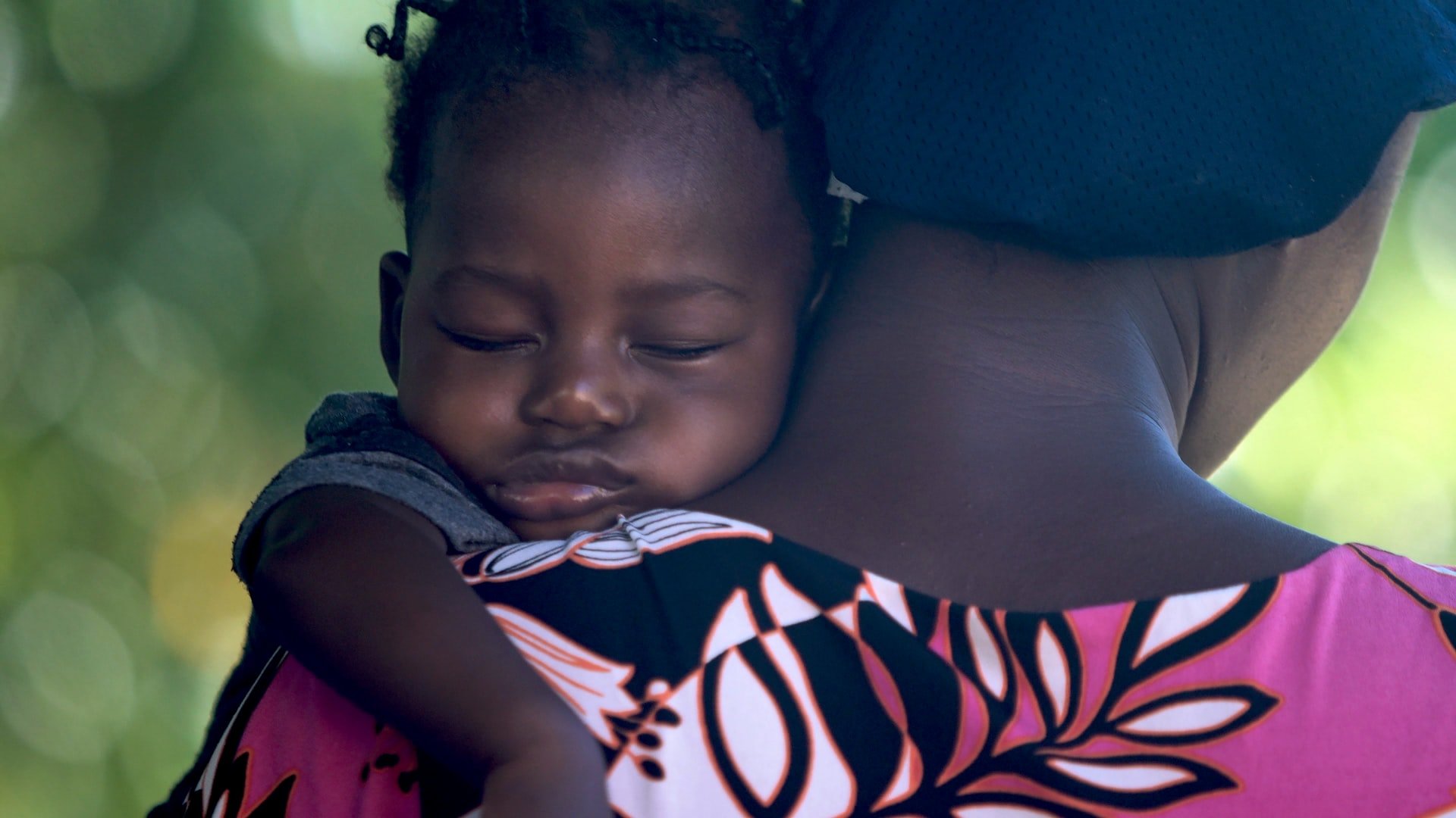 A baby being held while asleep on their mother's neck