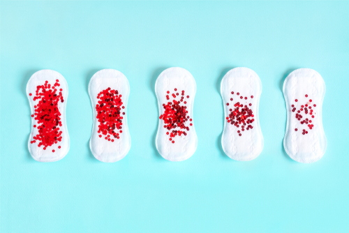 Menstrual pad with red glitter on blue colored background
